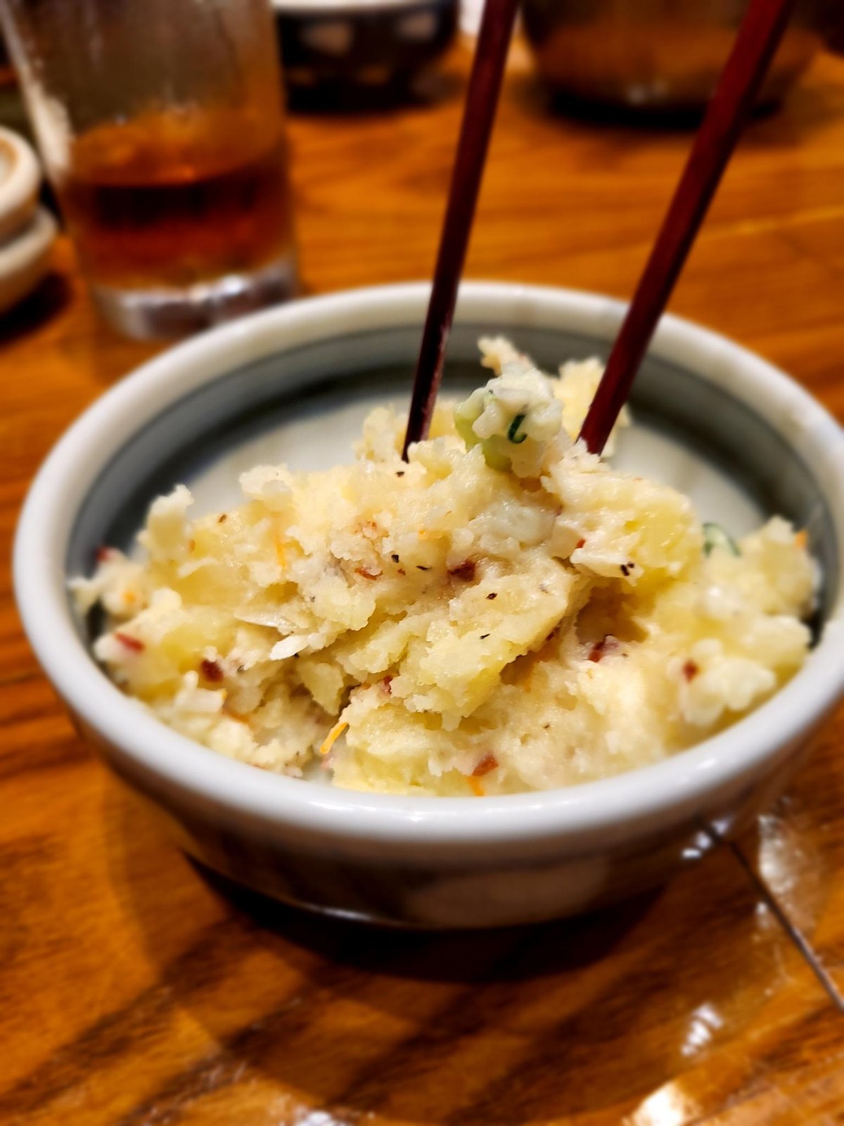 Japanischer Kartoffelsalat mit Stäbchen – typisches Beispiel für schlechte Tischsitten und Esskultur in Japan, weil die Stäbchen darin stecken.